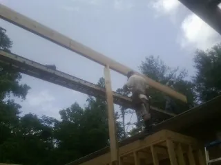 Carpenter setting a ridge beam over a new addition frame — Ice Dam Removal by Roofing Brothers in Rodeo
