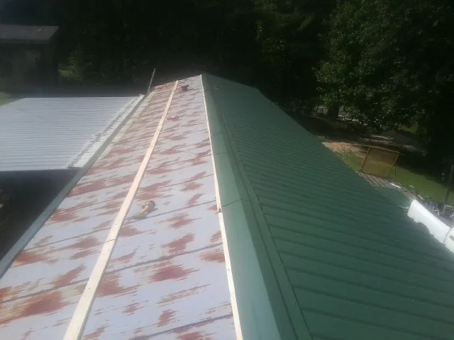 Old rusted panels beside newly installed green metal roofing — Wind Damage Roof Repair by Roofing Brothers in Rodeo