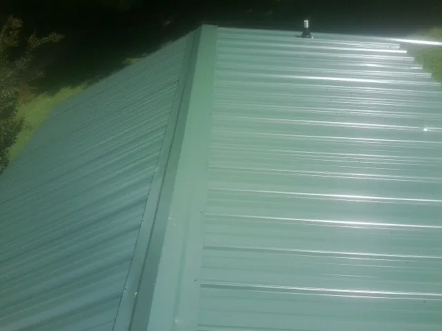 New green metal panels meeting at the ridge of a roof — Flat Roof Repair work by our crew in Rodeo