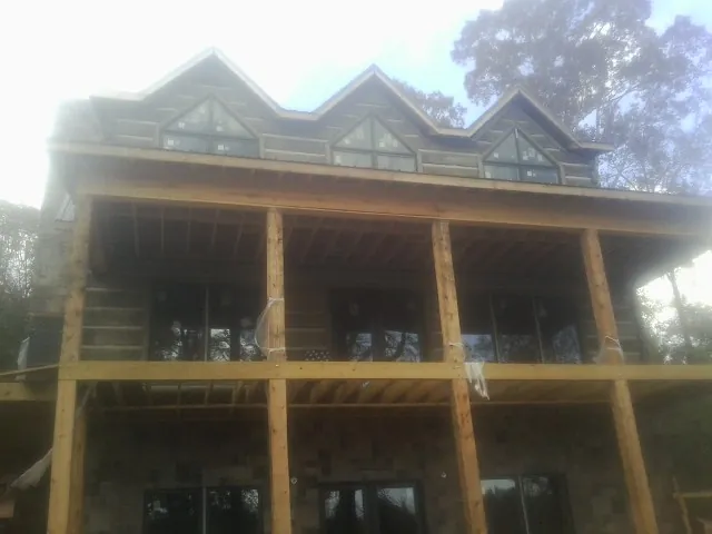 Dormers and porch framing on a large log home under construction — Roof Coating work by our crew in Rodeo