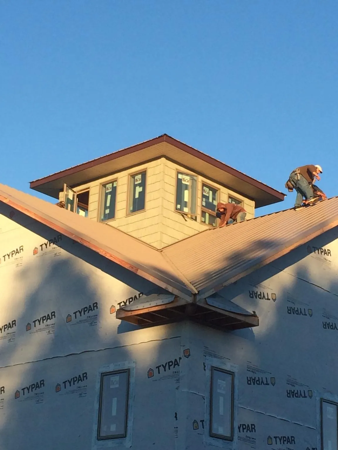 Roofers working around a rooftop cupola on a new metal roof at sunset — Roof Waterproofing in Rodeo by Roofing Brothers